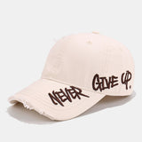 Opotrebovaný džínový klobúk s rozstrapkaným okrajom a vyšitým sloganom „Never Give Up“